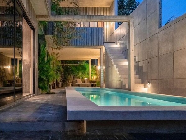 Relax by the pool in a serene outdoor space surrounded by lush greenery.