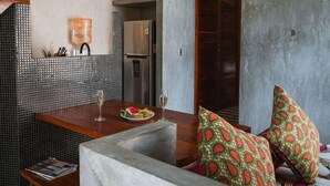 A modern kitchen with a dining area, featuring a wooden table, chairs, and a refrigerator. - CASA T -  Chic, Modern Villa with 3 Master Suites, AC & Pool  (Tulum)