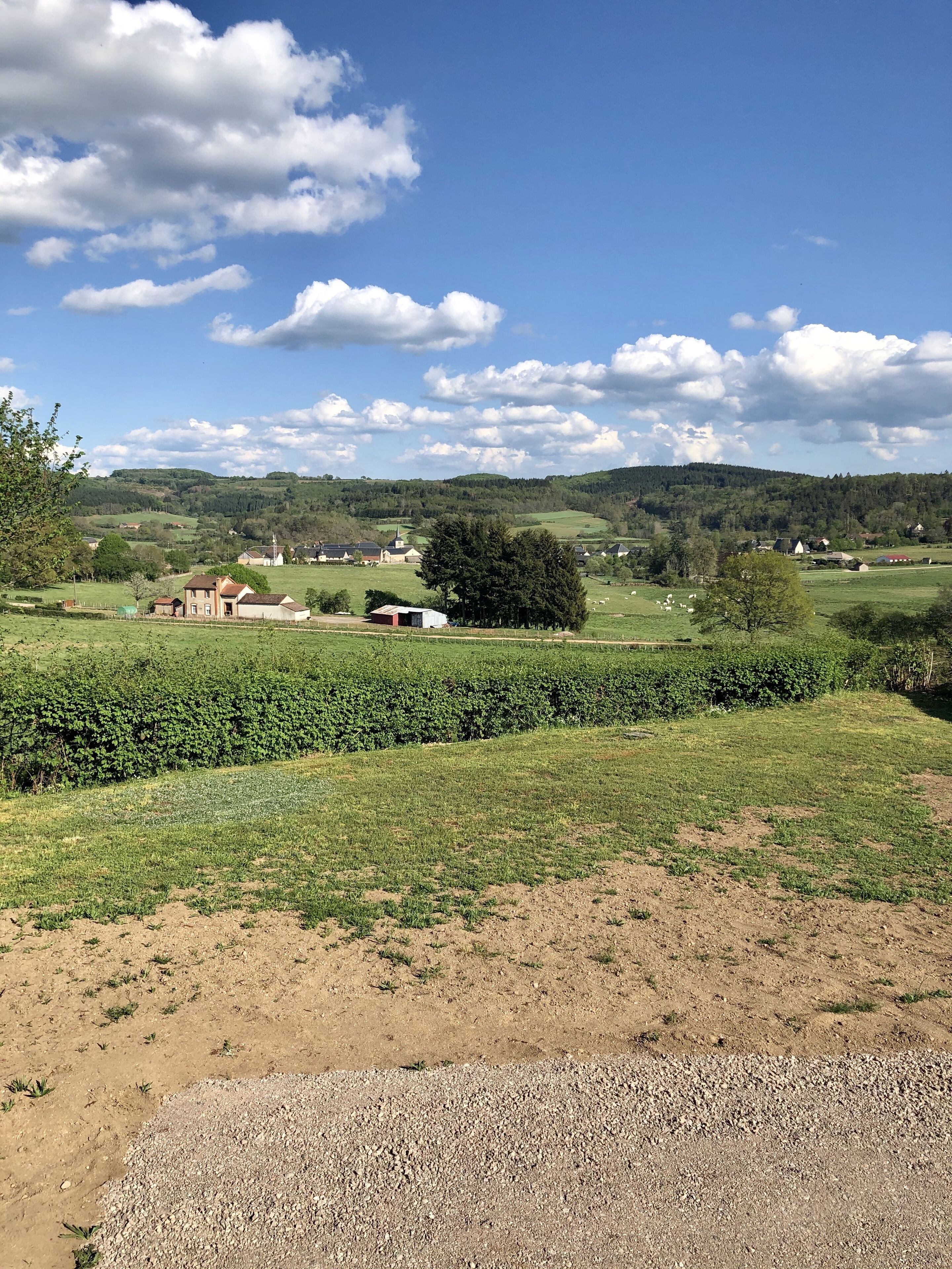 Paisaje rural con campos, un camino de grava y edificios dispersos.