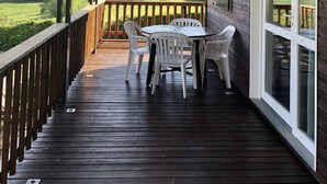 A wooden deck with a table and chairs, overlooking a green landscape.