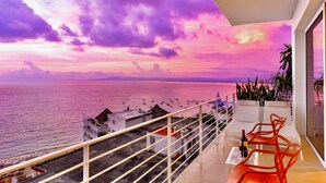 Un balcón con vista al mar y al atardecer.