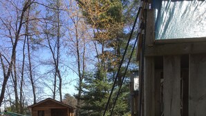 A child on a swing with a yellow slide, surrounded by trees and a wooden play structure. - Beautiful views of Lake Wissota @ Hideaway Resort- Cedar 4 cabin (Chippewa Falls)