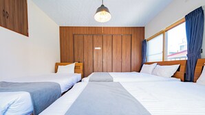 Une chambre d’hôtel avec deux lits simples, des têtes de lit en bois, une grande fenêtre avec des rideaux et un luminaire suspendu.
