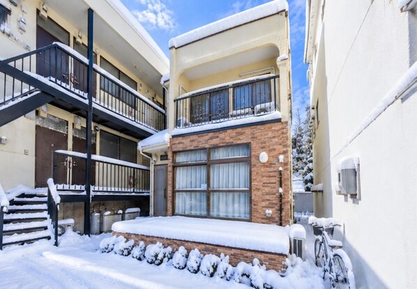 A multi-story building with a snow-covered entrance and a staircase leading to the upper floors.