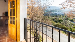 A wooden door leading to a balcony with a view of a town and mountains. - Complex of 3 apartments with swimming pool (Melegís)