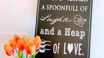 A decorative sign with a message about love and patience, placed above a vase of orange tulips.