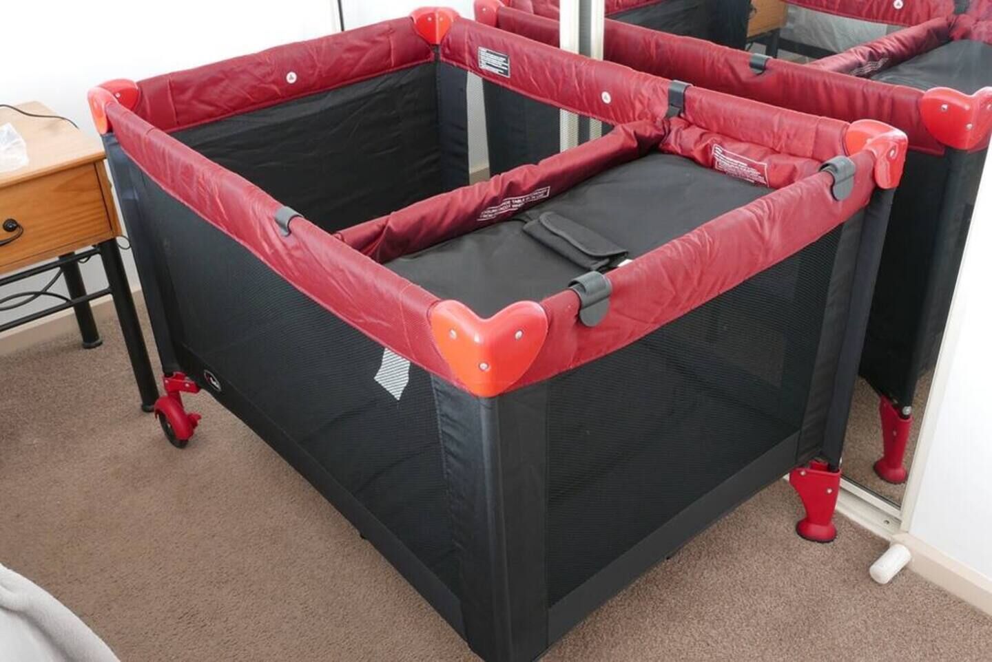 A red and black tent-like structure with wheels, possibly a play tent or storage unit.