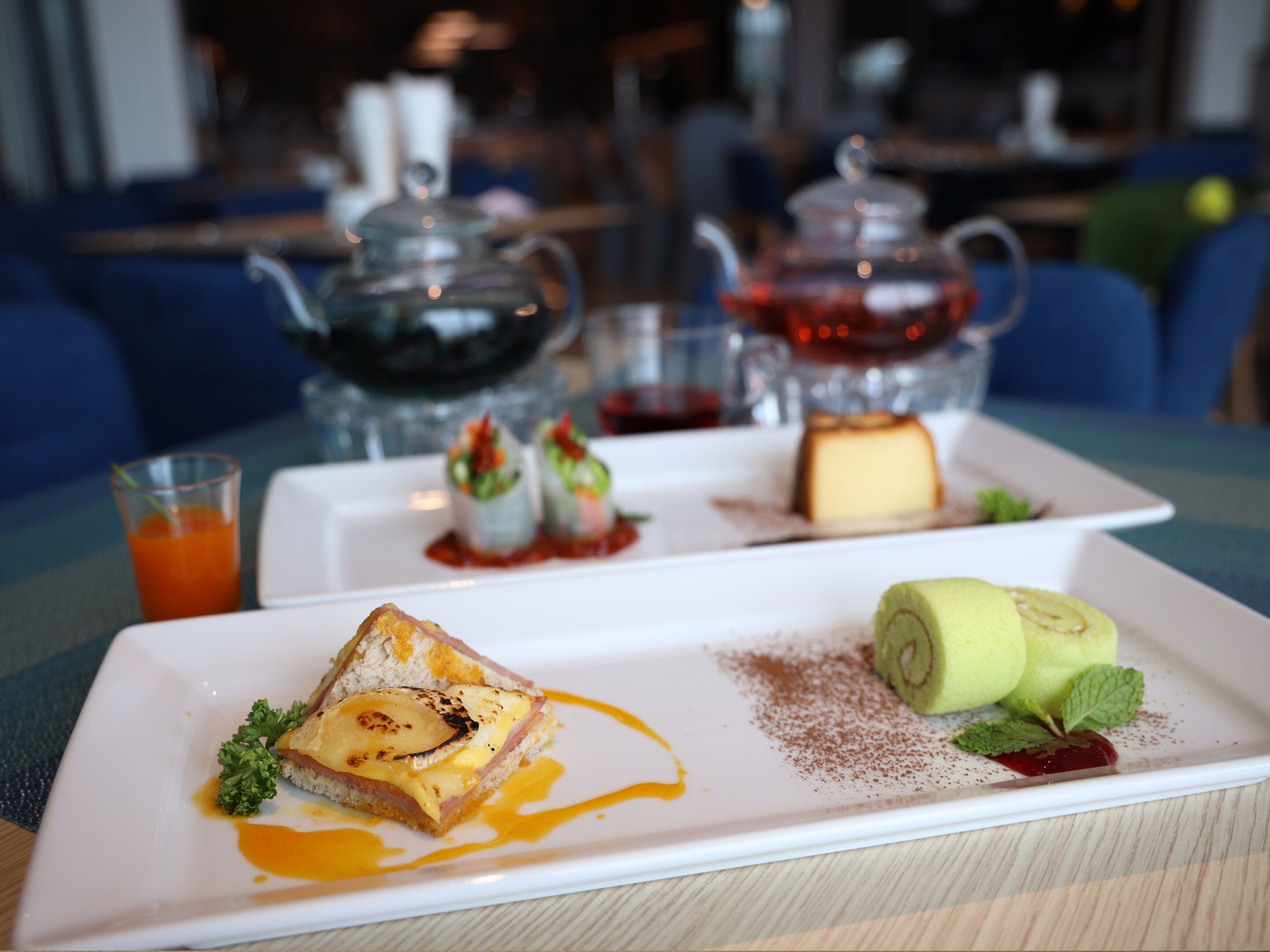 A dessert plate with a slice of cake, a rolled fruit, and a small green garnish.