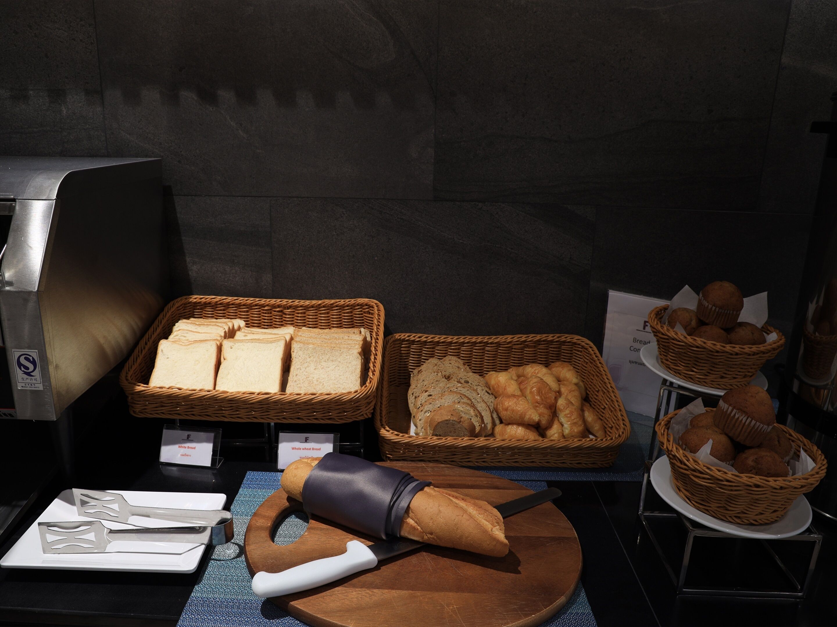 Mostra de forn amb diferents tipus de pa i pastissos, incloent pa integral, croissants i muffins.