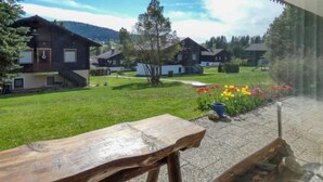 A view of a residential area with houses, a grassy lawn, and a flower bed with red and yellow flowers. - Am Hohen Bogen by Interhome (Arrach)