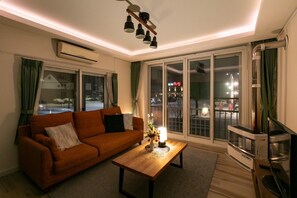 A living room with a sofa, a coffee table, and a TV stand. - The Sunlight (Sapporo)
