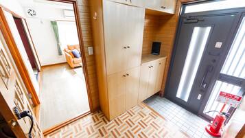 A hotel room with wooden flooring, a sofa, cabinets, and a fire extinguisher.