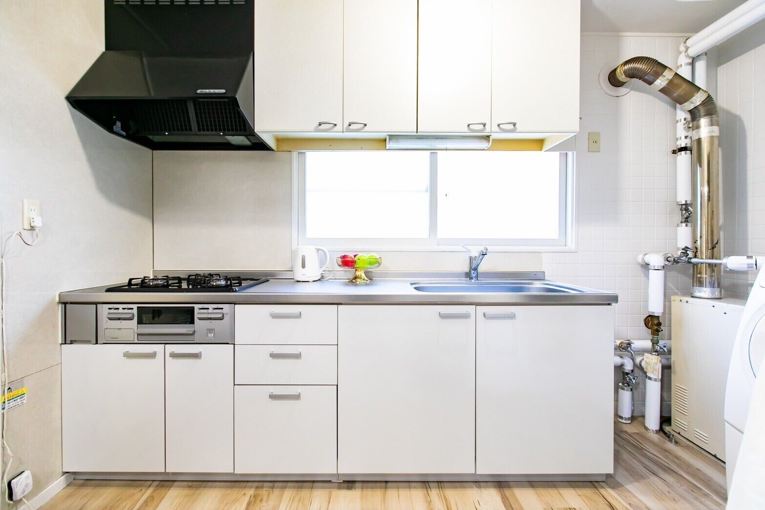 A modern kitchen with a gas stove, a built-in oven, a sink, and a window above the countertop.