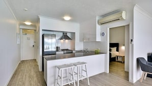 A modern kitchen with white cabinetry, a central island with stools, and a built-in stove.