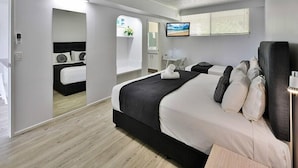 A modern hotel room with a large bed, a ceiling fan, a TV, and a bathroom visible through an open door.