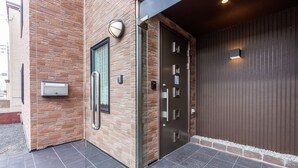 Une entrée moderne, avec une façade en briques, une porte en verre dotée d’une poignée et un portail en métal.