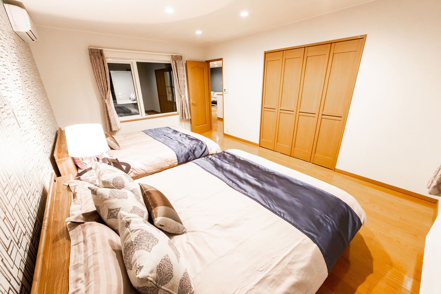 A hotel room with two beds, a wardrobe, and a window with curtains.