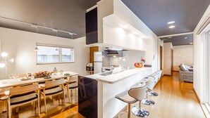Une cuisine moderne dotée d’un îlot central, de tabourets de bar et d’un coin repas avec une table dressée pour quatre personnes.