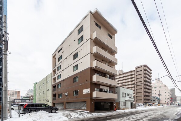 A multi-story building with a flat roof, several balconies, and a parking garage.