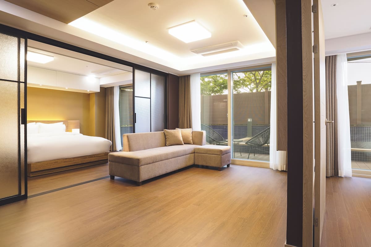 Una habitación de hotel moderna con una cama grande, un sofá y un ventanal corredero que da a un balcón.