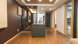 Een hotel lobby met een receptiebalie, houten vloeren en uitzicht op de gang naar de kamers.