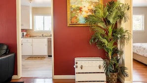 A room with a red wall, a framed painting, a potted plant, and a vintage suitcase. - Luxury stay near Santana Row for vacation/business (San Jose)