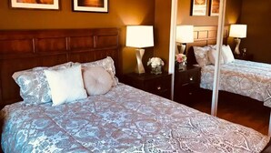 A hotel room with a large bed, two bedside tables, a mirror, and two framed pictures on the wall. - Luxury stay near Santana Row for vacation/business (San Jose)