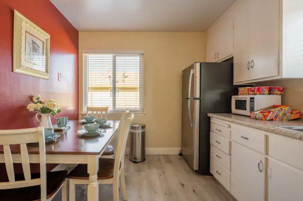 A compact kitchen with a dining table, chairs, a refrigerator, a microwave, and cabinets.