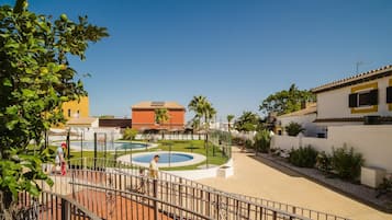 Un patio con piscina, zona cercada y edificios de estilo mediterráneo.