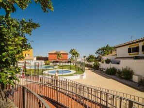 A courtyard with a swimming pool, a fenced area, and buildings with a Mediterranean architectural style.