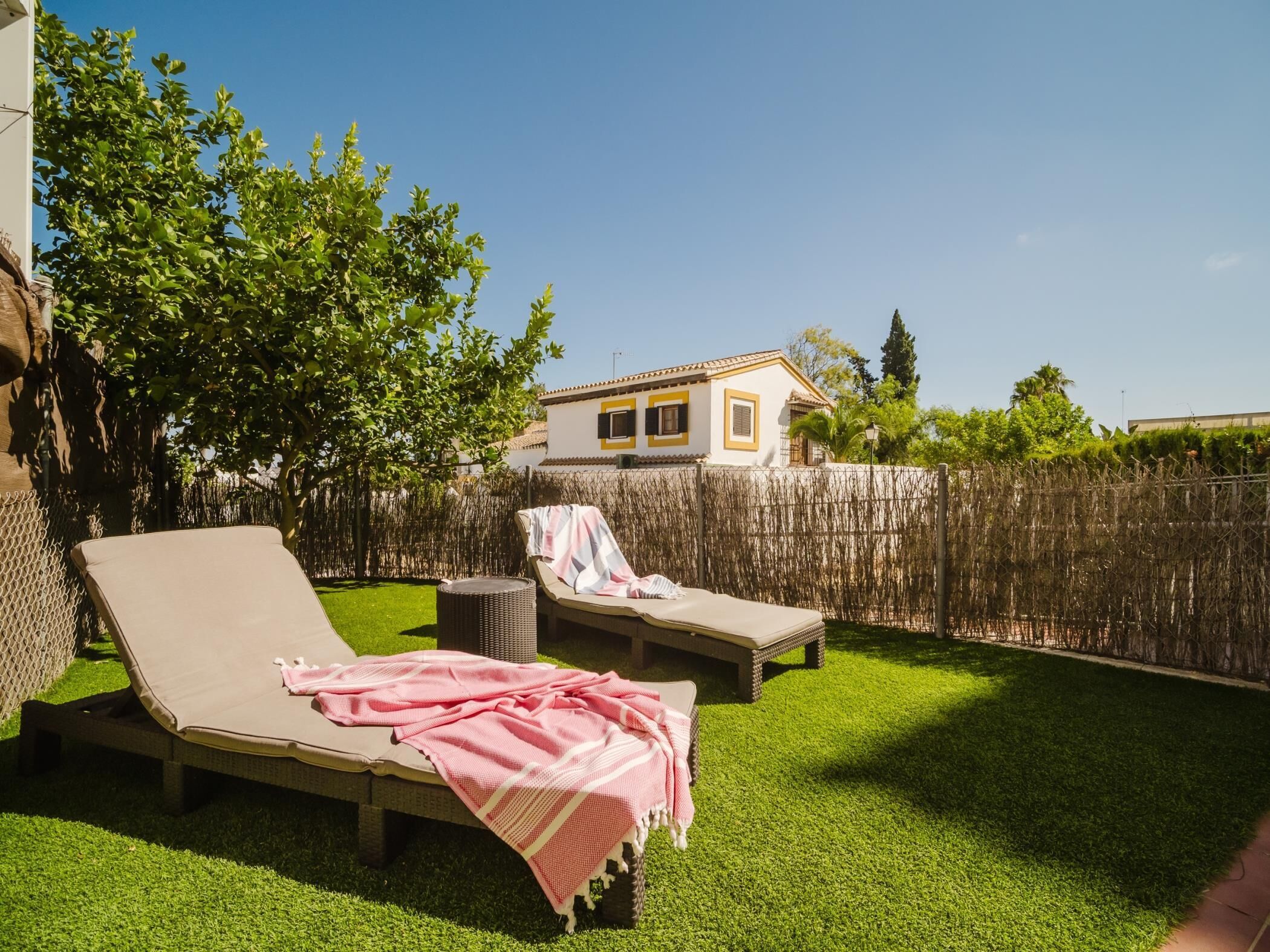Un patio trasero con dos sillones, una mesita y una cerca de madera.