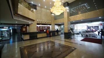 A spacious lobby with a large chandelier, a reception desk, and a car entrance.