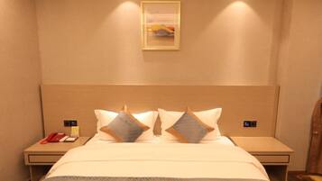 Una habitación de hotel con una cama grande, dos mesitas de noche, una lámpara de noche y un cuadro en la pared, además de un teléfono rojo sobre la mesita de noche.