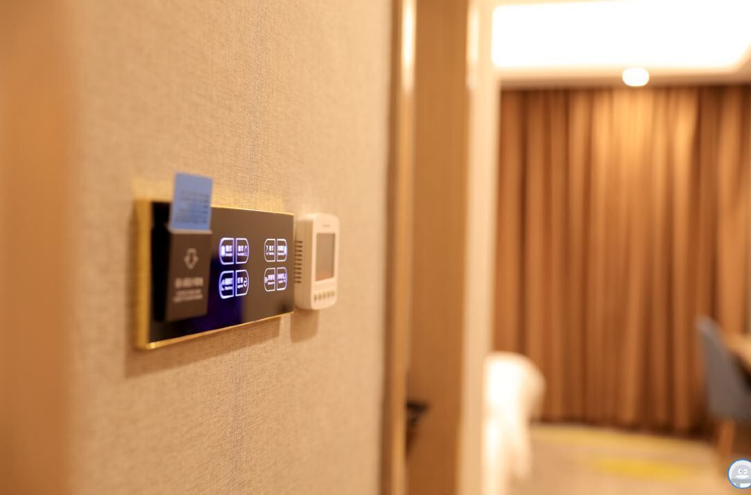 Panel de control instalado en la pared con varios iconos, probablemente para los servicios de la habitación.