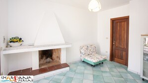Ein Zimmer mit Kamin, einem Sessel und einer Holztür.