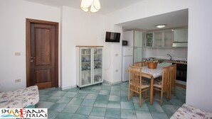 Eine kompakte Küche mit Essbereich, einer Holztür, einem Fernseher und einem Kühlschrank.