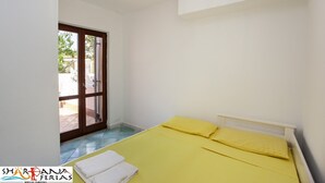 Ein Zimmer mit Bett, einer zur Außenwelt führenden Tür und einer Deckenleuchte.