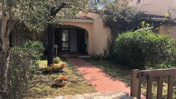 A stone wall, a paved pathway, and a building entrance with a door and windows. - Appartamento Le Querce 4 (San Teodoro)