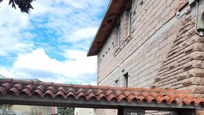 A narrow alleyway with a tiled roof overhead, a stone wall, and a metal gate. - Magomadas Enjoy House (Magomadas)