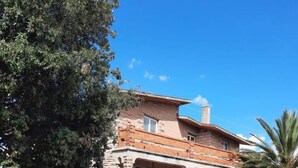 A two-story stone house with a balcony, a garage, and a parked car. - Magomadas Enjoy House (Magomadas)