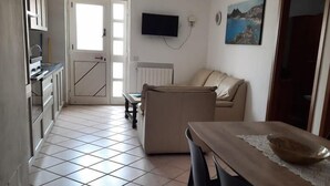 A kitchen with a dining area, a TV mounted on the wall, and a painting on the wall. - Magomadas Enjoy House (Magomadas)