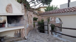 Un sendero de piedra que conduce a un muro de piedra con chimenea y zona de estar al aire libre.