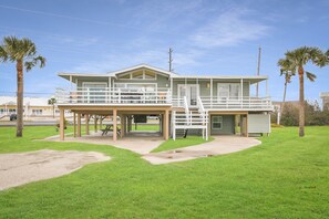 Ein zweistöckiges Haus mit überdachter Terrasse und einem kleinen Balkon.