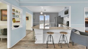 Une cuisine moderne dotée d’un îlot central, de tabourets de bar et offrant une vue sur la ville.