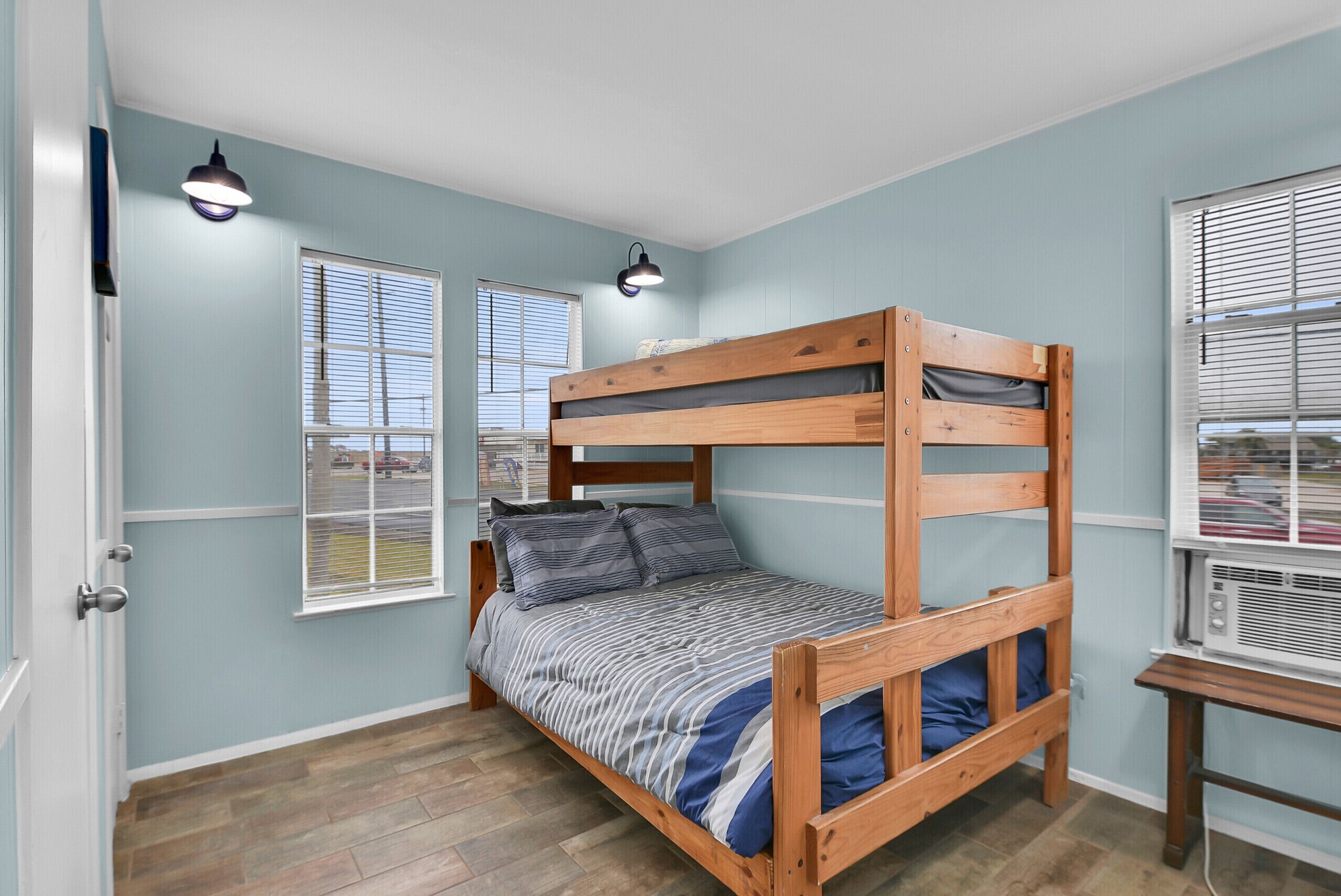 Habitación con literas, dos ventanas, un calentador y una puerta.