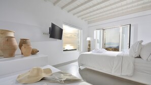 Une chambre moderne avec un grand lit, un téléviseur à écran plat et une vue sur le coucher de soleil par la fenêtre.