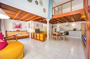 A spacious living area with a sofa, a dining table, and a kitchen in the background. - Artistic Loft Steps from Acropolis w/ Courtyard (Athina)
