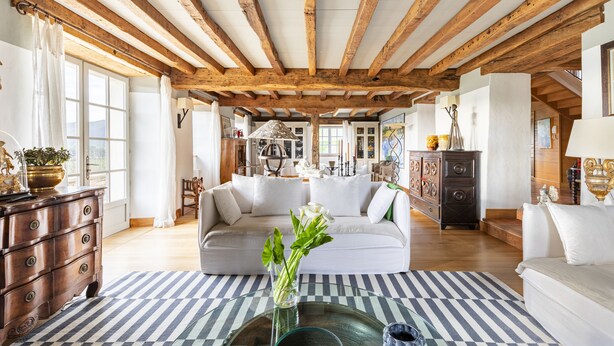 A spacious living room with a high wooden ceiling, a white sofa, a striped rug, and a glass coffee table. - Ferme Labourdine avec piscine 5 étoiles - Sare (Sare)