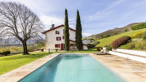 A rectangular swimming pool with a house in the background. - Ferme Labourdine avec piscine 5 étoiles - Sare (Sare)