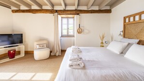A bedroom with a large bed, a TV, and a window with curtains. - Ferme Labourdine avec piscine 5 étoiles - Sare (Sare)